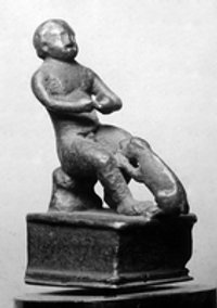 Statuette eines nackten sitzenden Knaben, der von einem Hund angesprungen wird